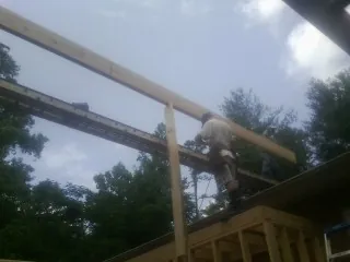Carpenter setting a ridge beam over a new addition frame — Ice Dam Removal by Roofing Brothers in Lawton
