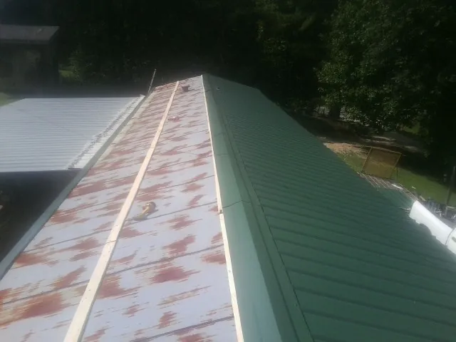 Old rusted panels beside newly installed green metal roofing — Wind Damage Roof Repair by Roofing Brothers in Lawton
