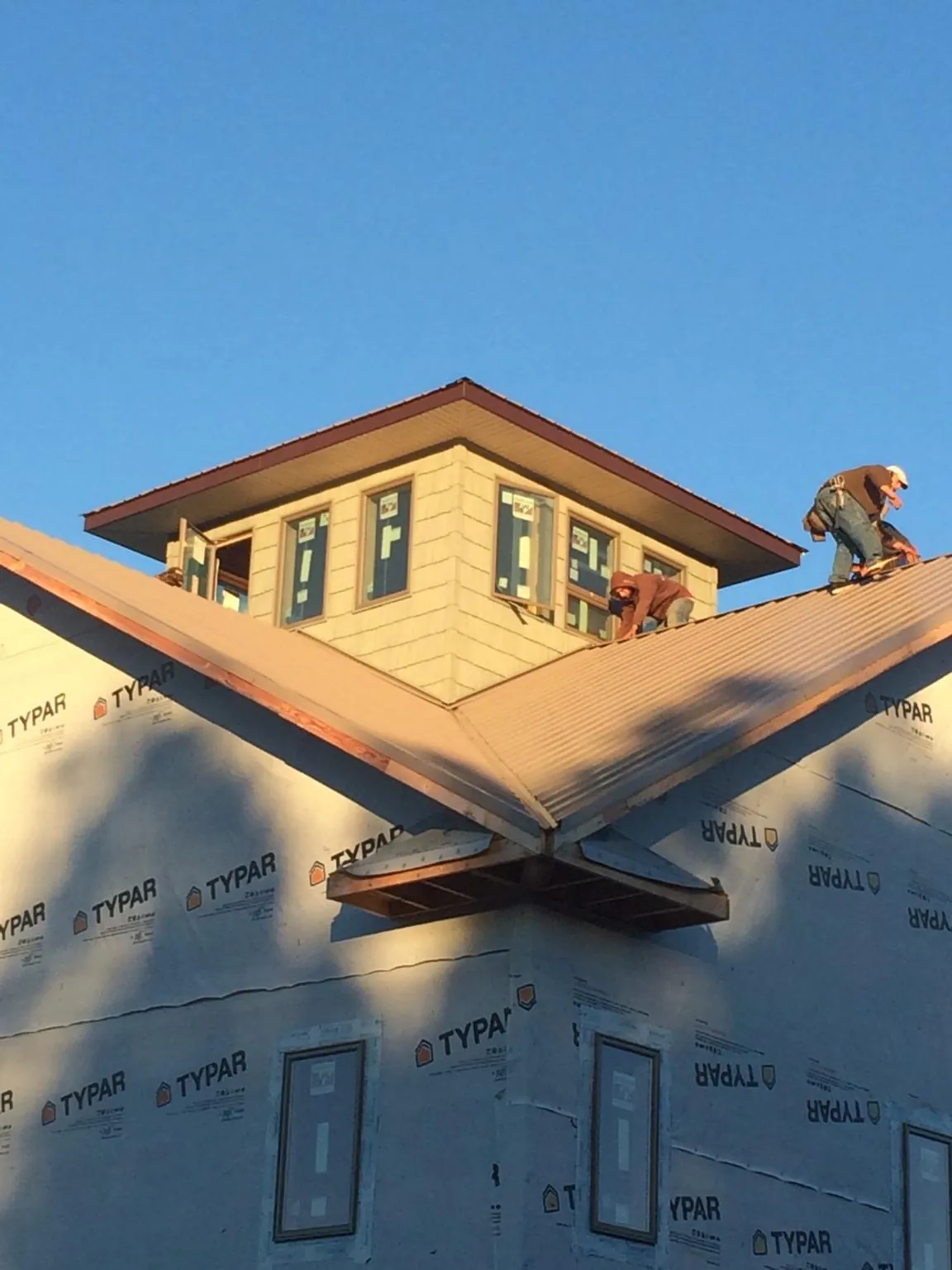 Roofers working around a rooftop cupola on a new metal roof at sunset — Roof Waterproofing in Lawton by Roofing Brothers
